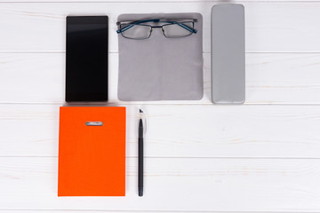 Orange diary with a pen, glasses on cloth for rubbing and mobile phone