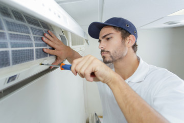 portrait of mid-adult male technician repairing air conditioner