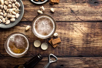 Fototapeten Zwei Gläser frisches Bier und salzige Snacks auf einem braunen Holztisch, Draufsicht und Platz für Text © Sunny Forest