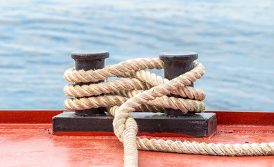 Mooring bollard with a fixed rope on the ship against the water background