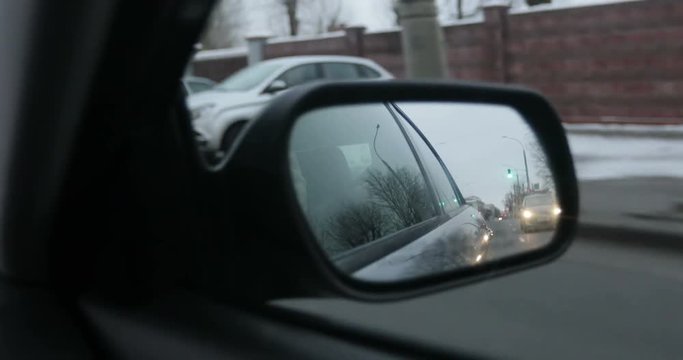 The view from the side mirror. City. Cars.