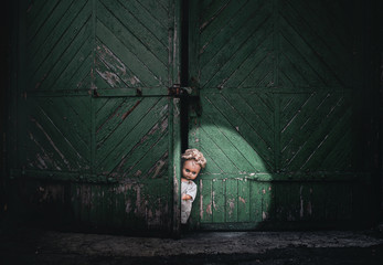 A terrible old doll peeks out from behind the old gate in the light of a bright spotlight....