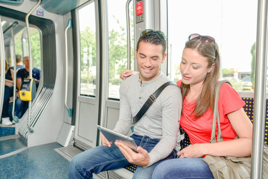 Couple using a tablet computer during a tram journey