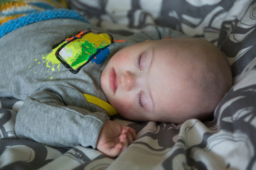 Cute baby boy with Down syndrome sleeping on the bed