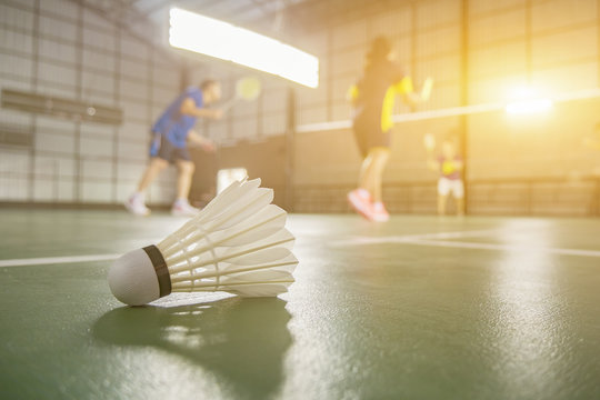 A set of badminton concept.Badminton ball (shuttlecock) and racket on court floor,Paddle ,the shuttlecock and badminton courts with players competing in modern gym,selective focus,vintage color