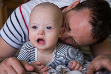 Cute baby boy with Down syndrome playing with dad