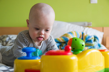 Cute baby boy with Down syndrome playing with toy