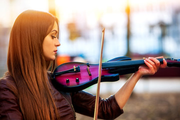 Busker woman perform music on violin in park outdoor. Sad beautiful girl performing jazz on city...
