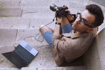 Young photographer viewing his photos on the back of the camera LCD display (Creativity, hobbies,...