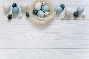 Blue and white Easter  eggs in nest on wooden background.