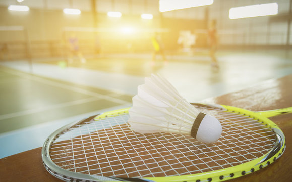 A set of badminton concept.Badminton ball (shuttlecock) and racket on court floor,Paddle and the shuttlecock and badminton courts with players competing in modern gym,selective focus,vintage color