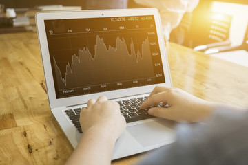 business man use  laptop computer computer for analyzing financial chart with good performance graph sitting at his desk,statistical reports spread writing business plan,vintage color,selective focus