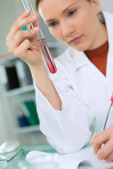 close-up of female scientist in overall holding tube