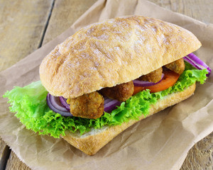 Fresh sandwich bread ciabatta onion, tomatoes, lettuce, beans cutlets on rough rustic wooden table background.