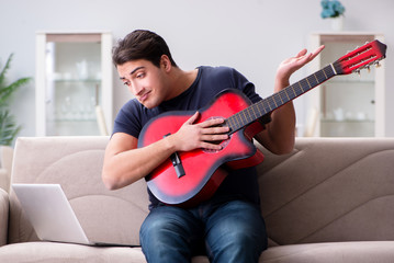 Young man practicing playing guitar at home
