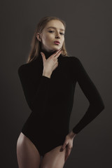 Model test with glamorous woman in black body over a grey studio background