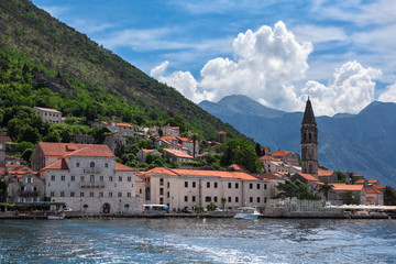 Fototapeta na wymiar View from boat at Perast cityscape with bank, ancient houses, fort tower and church. The Adriatic sea, Kotor gulf, Montenegro