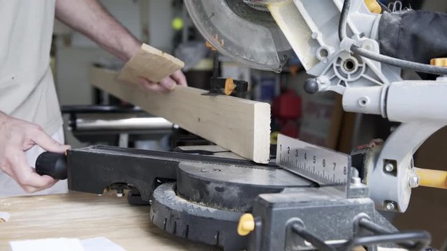 A homeowner handyman type using a power miter saw to cut baseboard for a home improvement project.