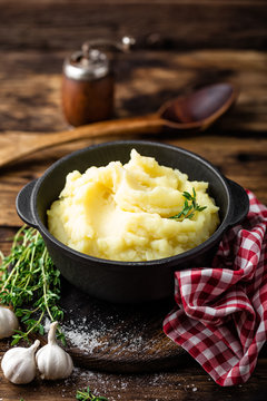 Mashed potatoes, boiled puree in cast iron pot on dark wooden rustic background