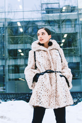 Beautiful business woman in a fur coat on a background of office on the street