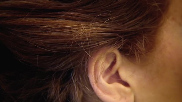 A harsh lady (woman in character) applying lipstick to her face in the bathroom, zoom in on her ear. Funny comedy shot.
