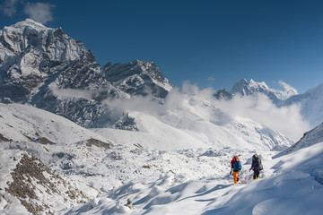 Fototapeta na wymiar Trekkers crossing Gokyo glacier in Khumbu valley on a way to Everest Base camp