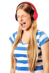 Young woman with headphones listening and singing to music, isolated on white