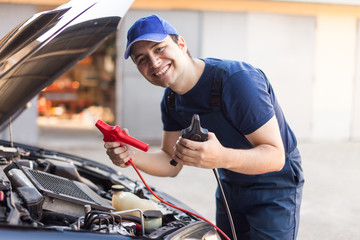 Mechanic using cables to start a car engine