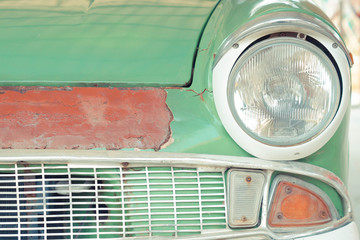 The front side of an old car with cracked paint vintage