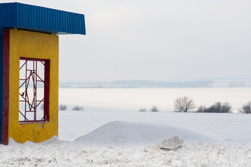 A colorful rural bus stop with snowy meadows in the winter