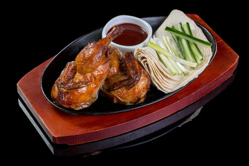 Grilled Chicken Tabaka in frying pan on dark background with reflection