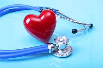 Medical stethoscope and red heart isolated on blue mirror background