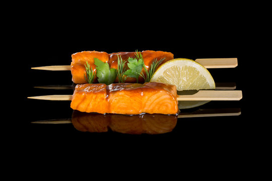 Salmon cooking on a grill. On a black background with reflection