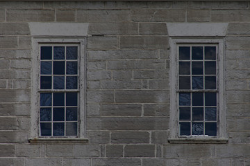 Two blue stained textured retangular windows on gray concrete block wall.