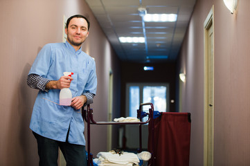Man cleaning hotel hall wearing blue coat