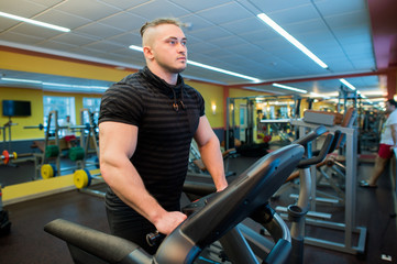Fototapeta na wymiar Attractive young muscular man while running on a treadmill in gym