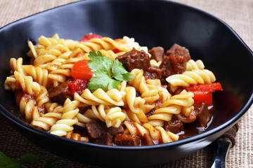 beef goulash, a stew that originated in Hungary, served with noodles and garnished with fresh chopped parsley