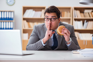 Fototapeta premium Hungry funny businessman eating junk food sandwich
