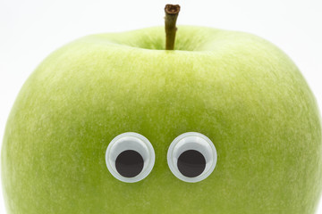green apple with googly eyes on white background - portrait