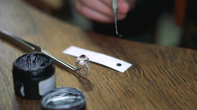 Jeweler takes the enamel for painting the silver ring with a tool