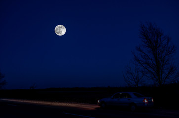Mountain Road through the forest on a full moon night. Scenic night landscape of dark blue sky with moon. Azerbaijan