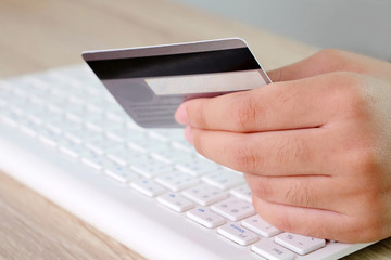Woman hands holding credit card over keyboard computer background, shopping online concept, business and technology