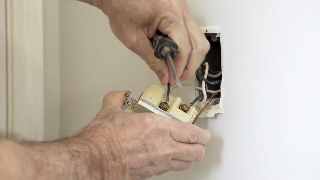 An electrician or handyman type installing wire nuts and pushing the wires into the junction box that is no longer in use.