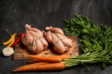 Young white cockerels chicken with herbs and spice before baking in the oven. Dark background for a...