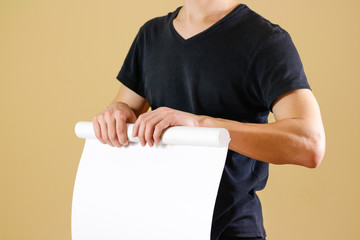 Guy holds in his hands twisted up in paper. Opens the package of paper. Shows a blank sheet rolled...