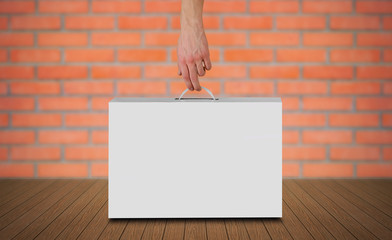 Hand holds a white box with a handle. Packing box for laptop. Isolated on grey background