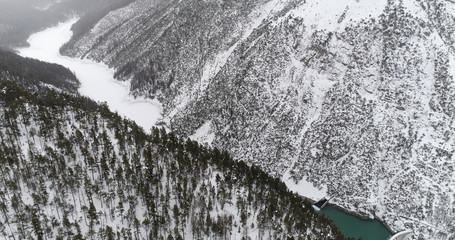 Aerial view of hydro power plant located in extreme high mountains. Winter season