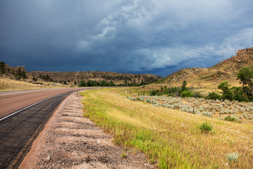 A road cuts through eastern Wyoming on a summer day during a storm.