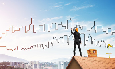Man architect draw silhouette of modern city on blue sky. Mixed media