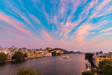 Naklejka premium Udaipur cityscape with colorful sky at sunset. The majestic city palace on Lake Pichola, travel destination in Rajasthan, India